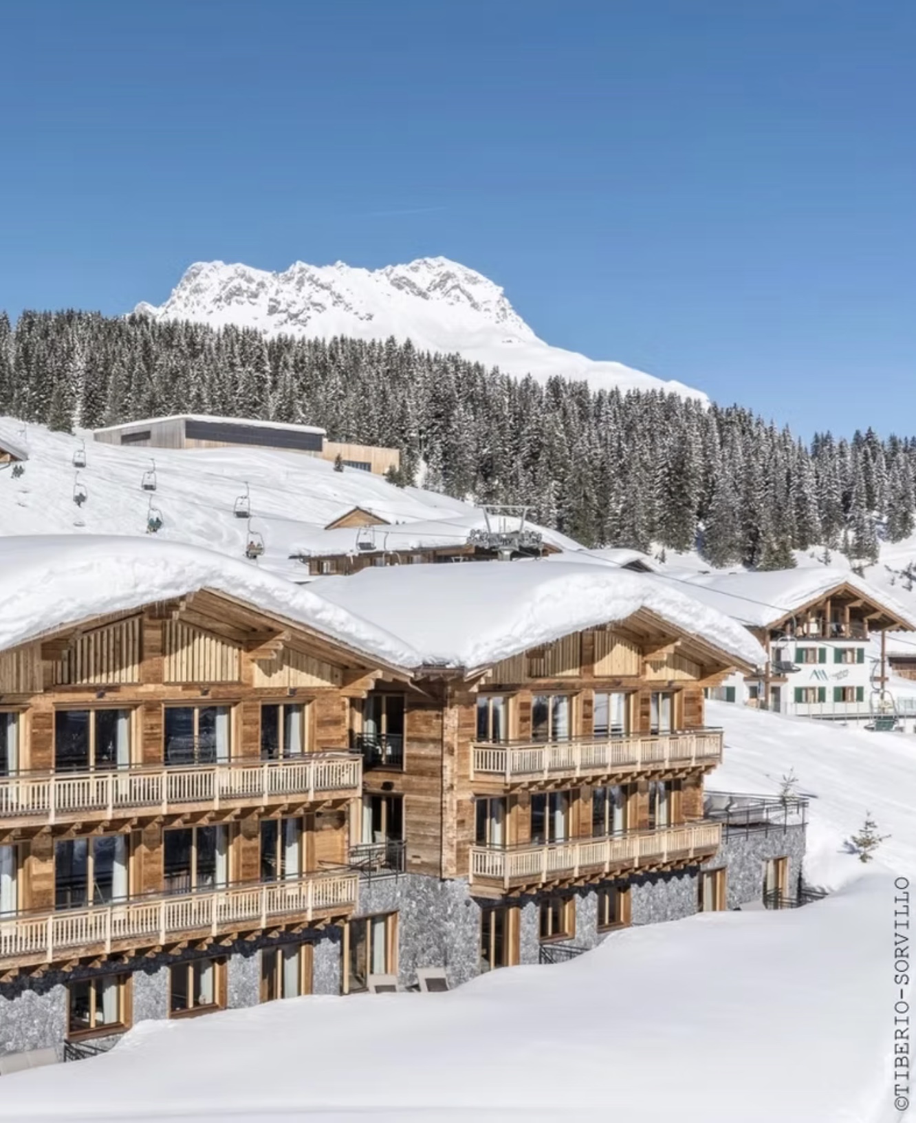 Luxuriöse Arula Chalets in Lech am Arlberg direkt an der Skipiste mit verschneiter Alpenlandschaft.